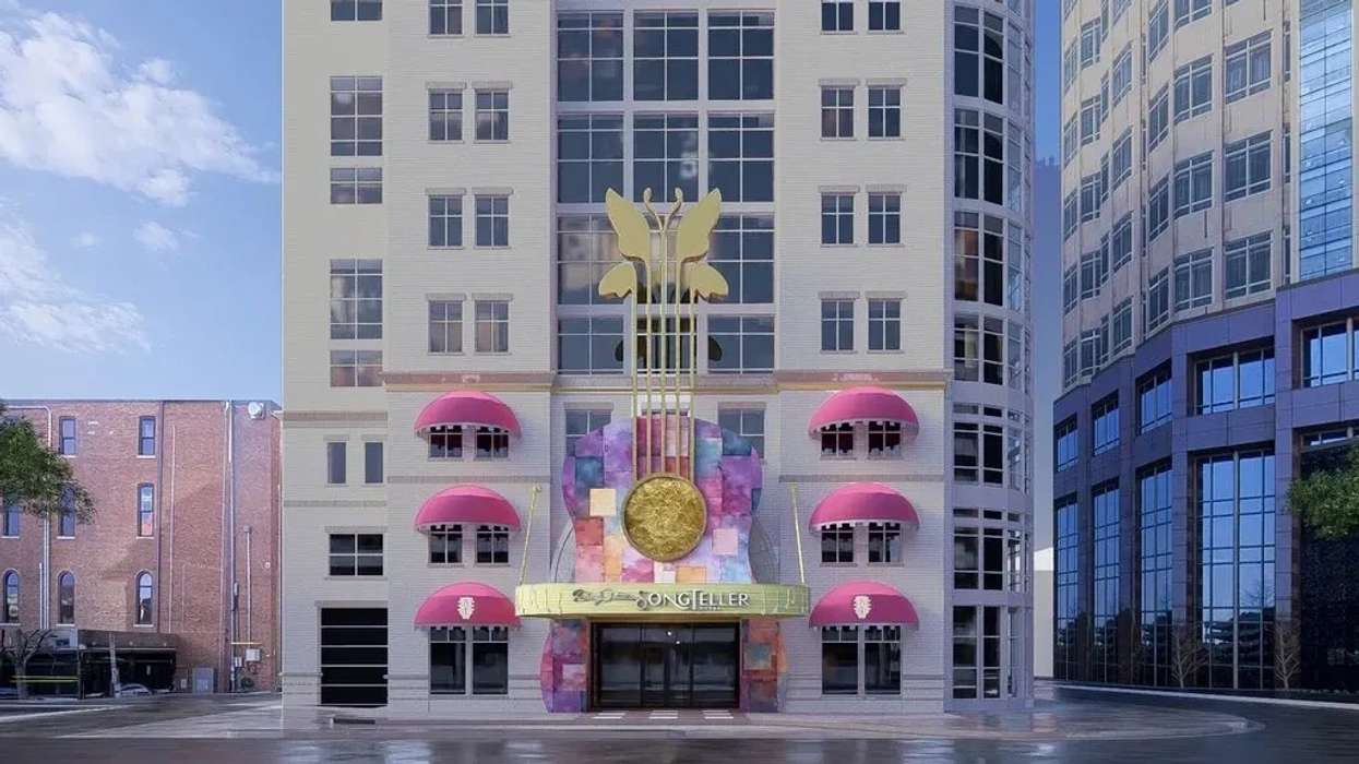 Building with pink awnings, gold emblem, and colorful entrance against a blue sky.