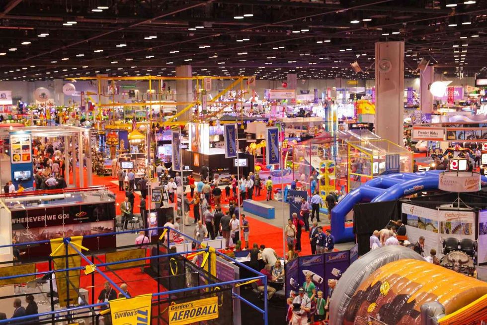 Busy trade show floor with colorful booths and crowds of visitors.