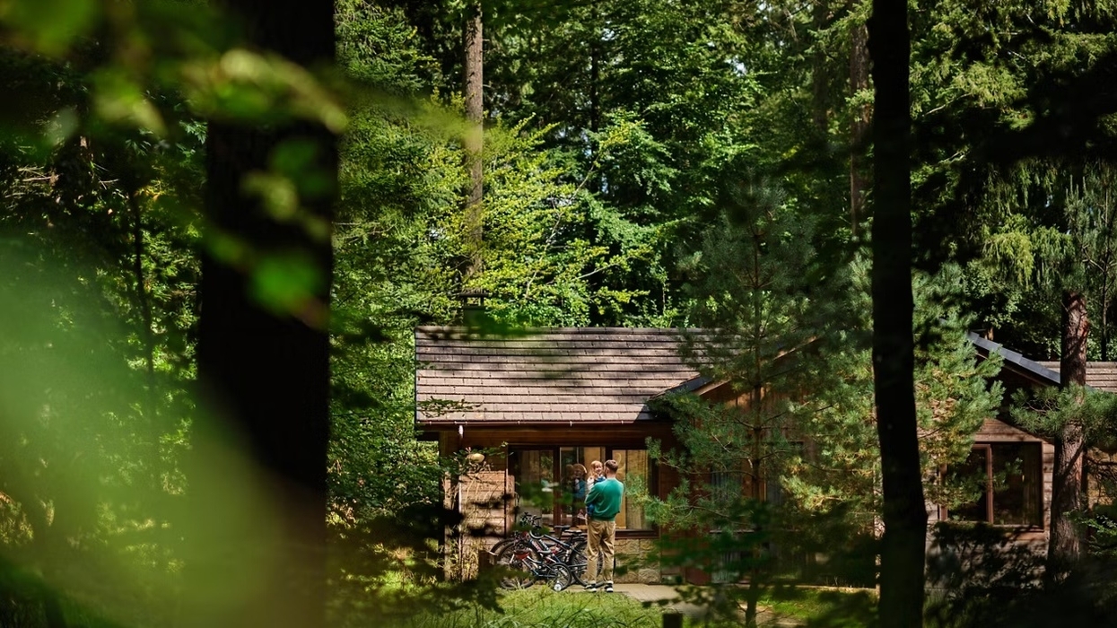 Cabin in a lush forest at Center Parcs with two people and bikes in front.