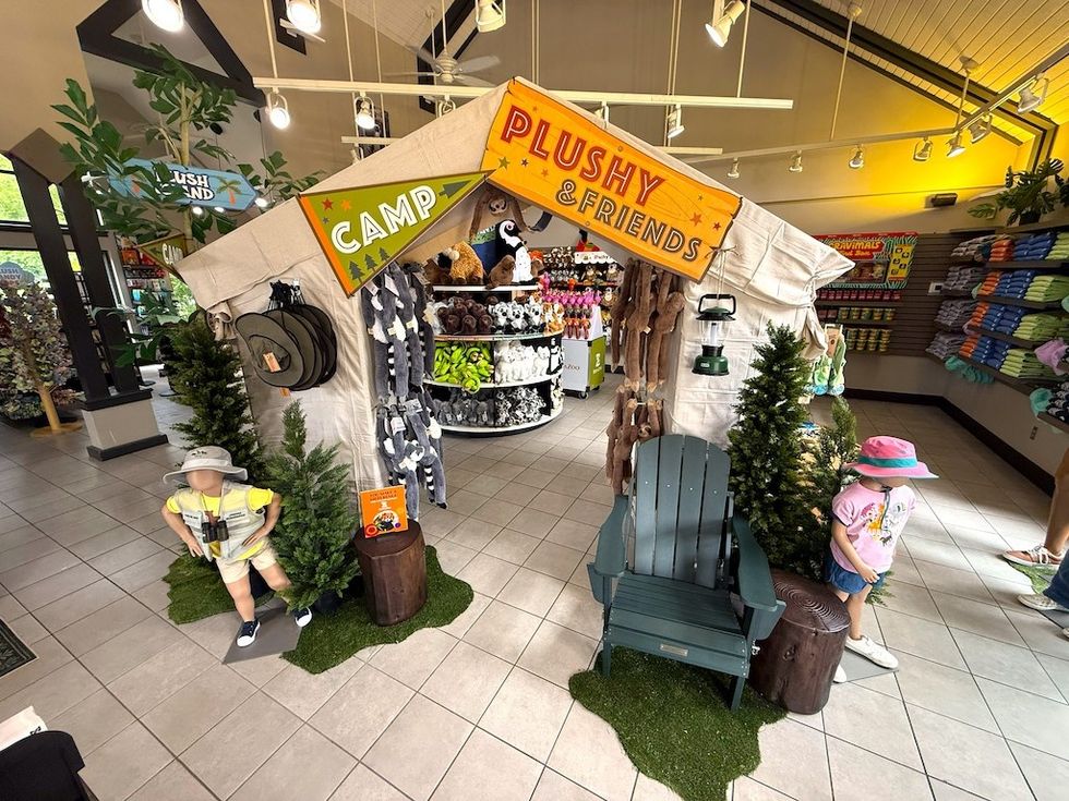Camping-themed plush toy display with tents and mannequins in Tulsa Zoo store setting.