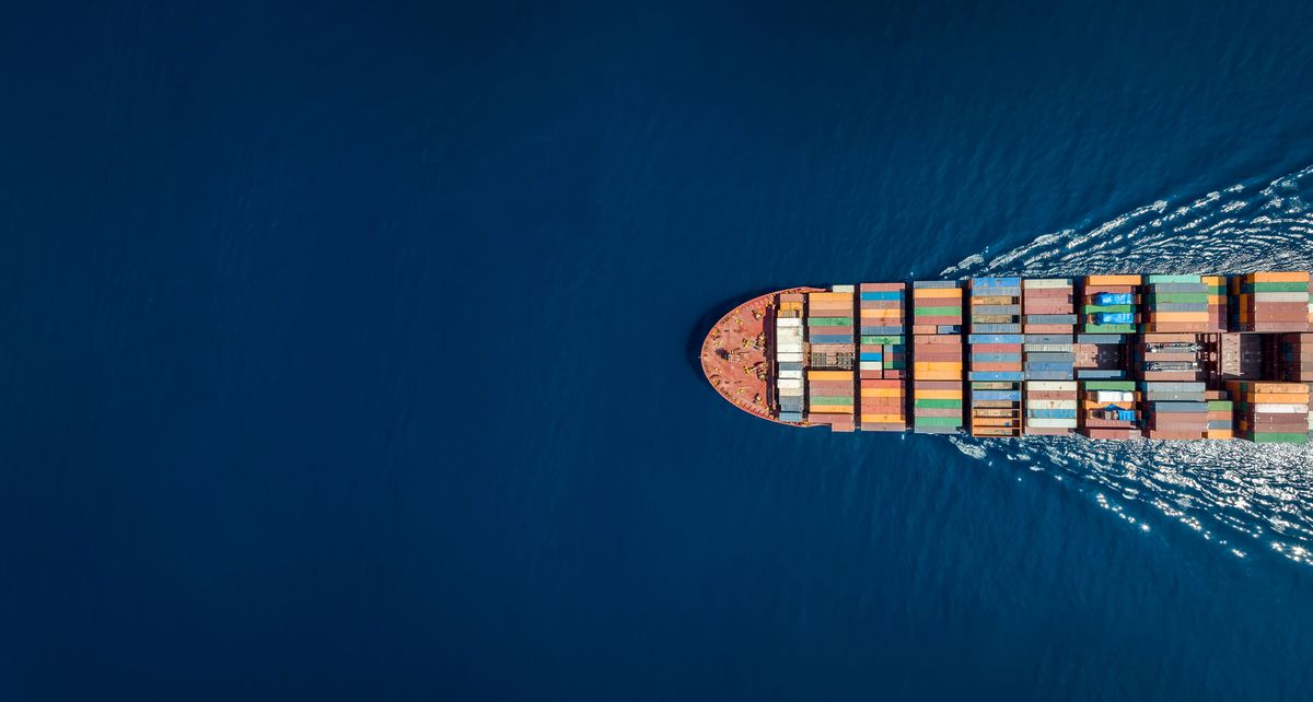 Cargo ship with colorful containers sails through deep blue sea.