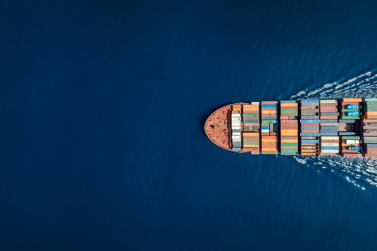 Cargo ship with colorful containers sails through deep blue sea.