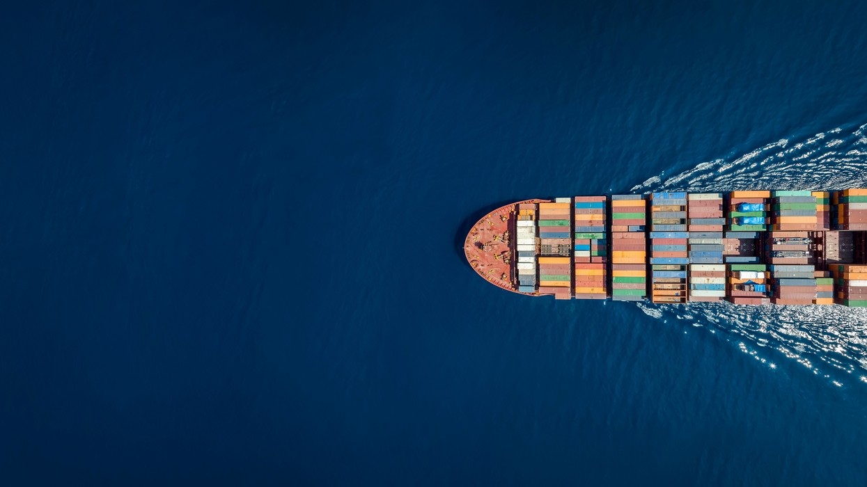 Cargo ship with colorful containers sails through deep blue sea.