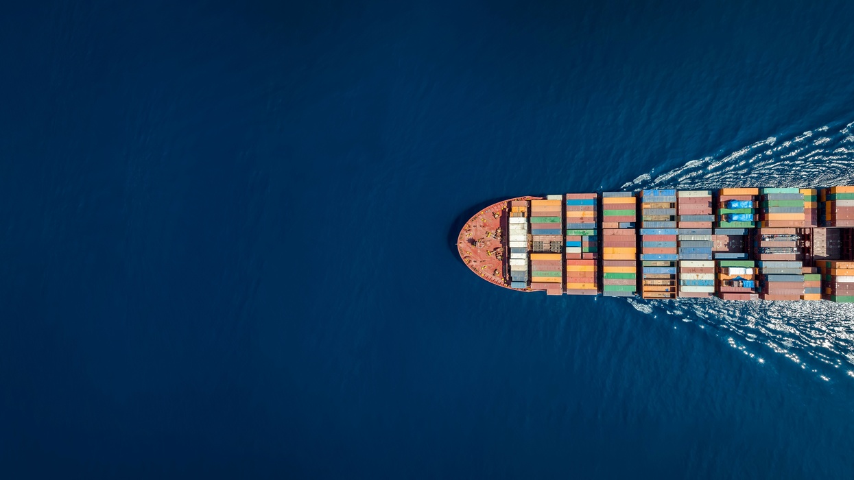 Cargo ship with colorful containers sails through deep blue sea.