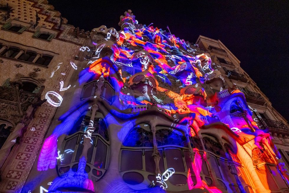 Casa Batllo facade lit with vibrant, colorful projections at night.
