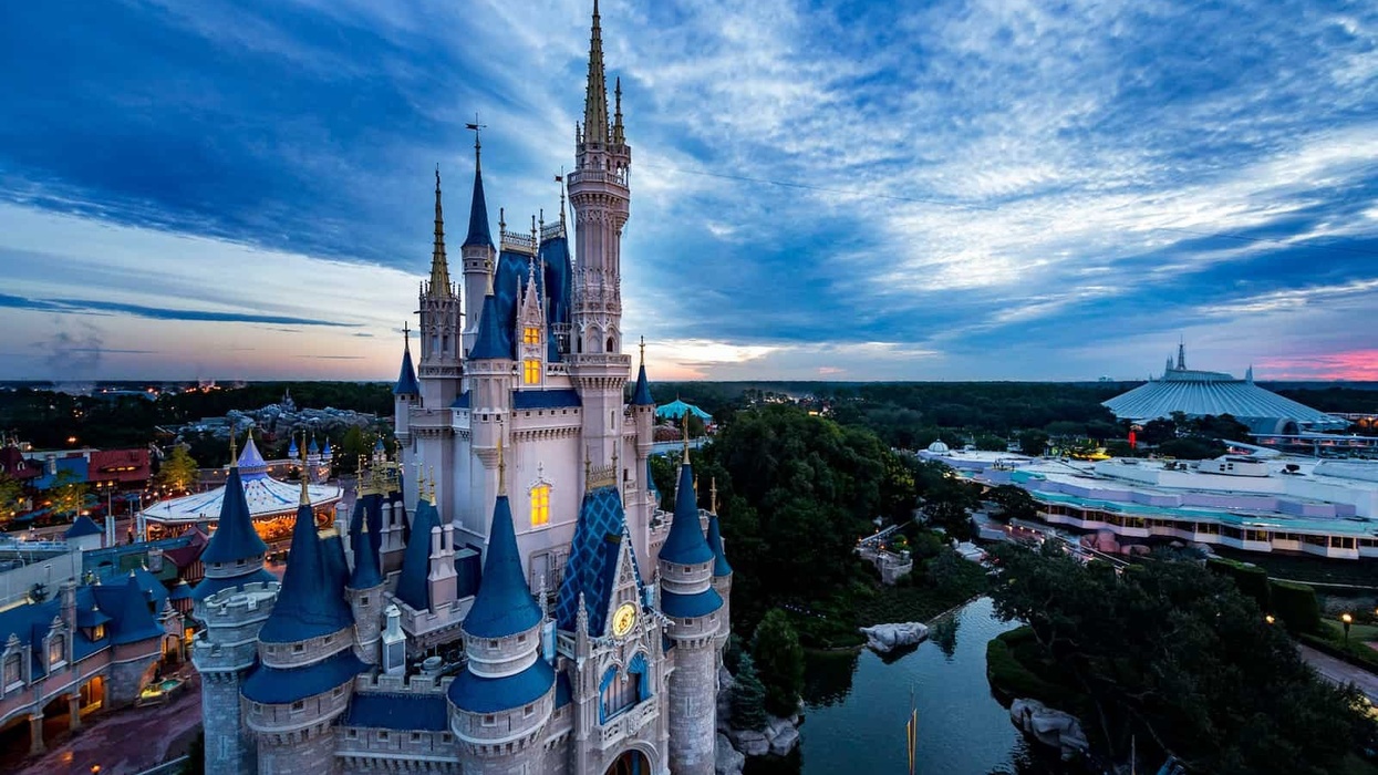 Castle at Magic Kingdom theme park during sunset with dramatic clouds.