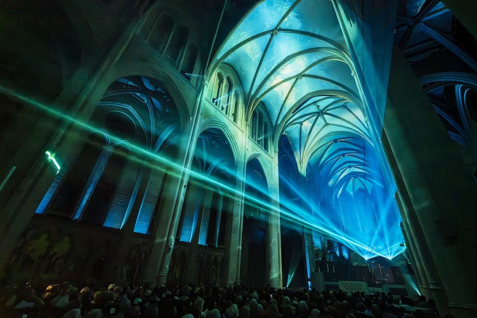 Cathedral interior with blue lights and lasers illuminating the arched ceiling.