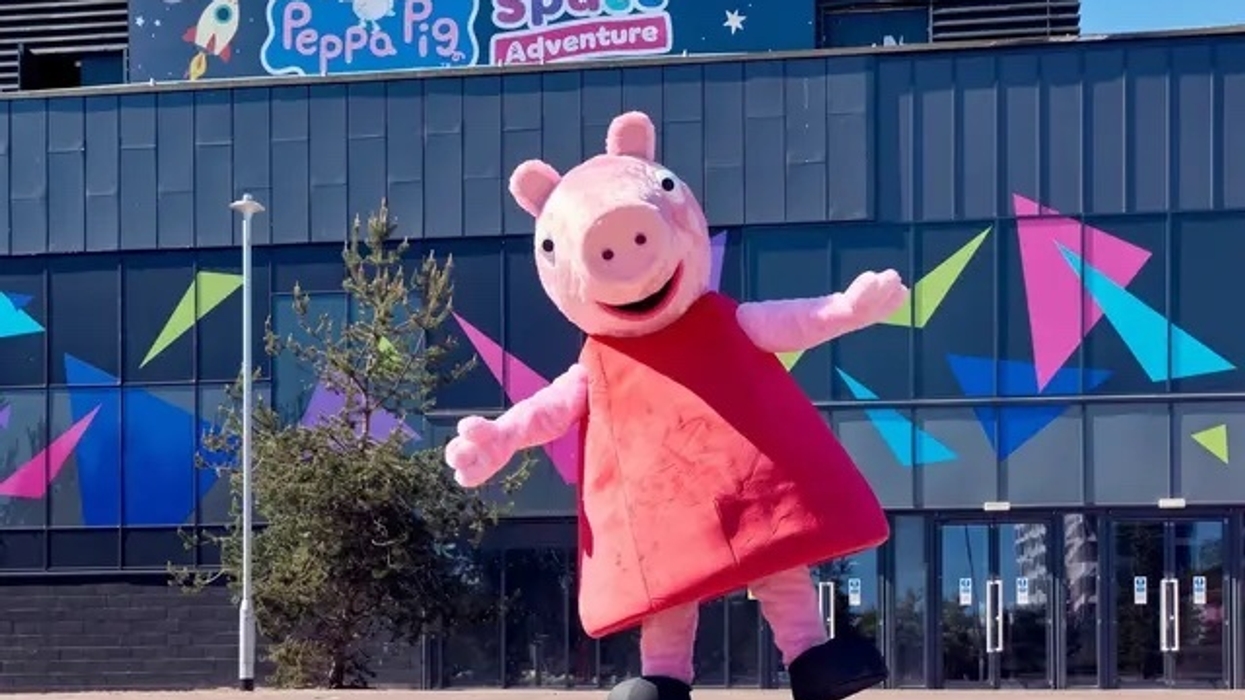 Character in a pig costume outside "Peppa Pig Space Adventure" building.