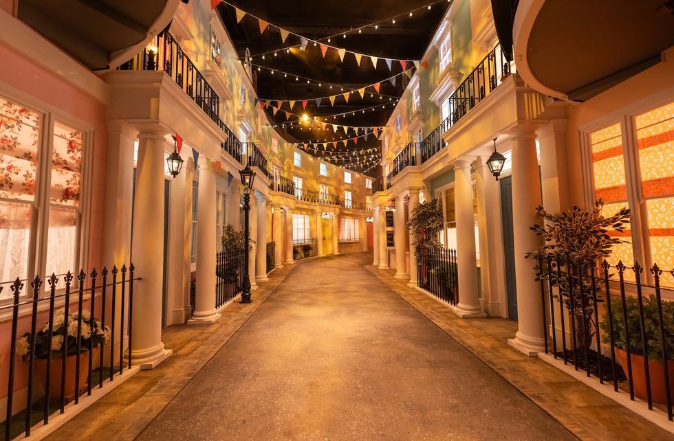 Charming street scene with colorful buildings, string lights, and festive bunting overhead.