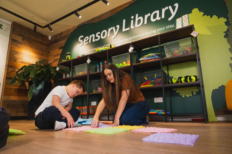 Child and adult engage with sensory mats in a library setting.