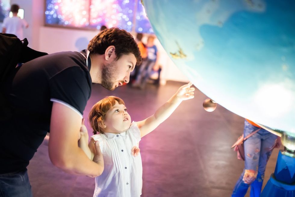 Child and adult pointing at a large globe in an exhibit.