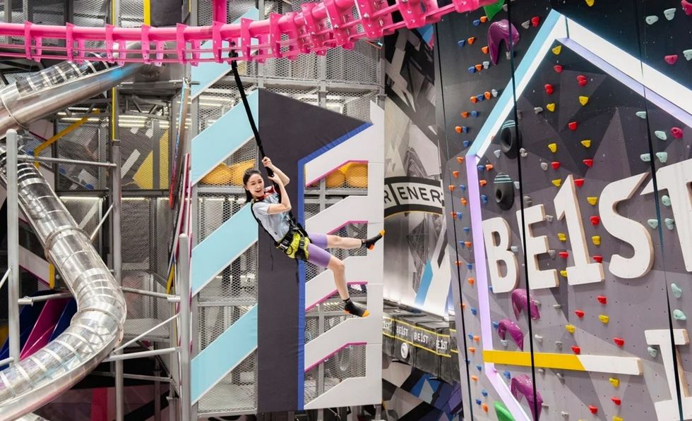 Child climbing in a BE1ST indoor adventure park with colourful walls and structures.