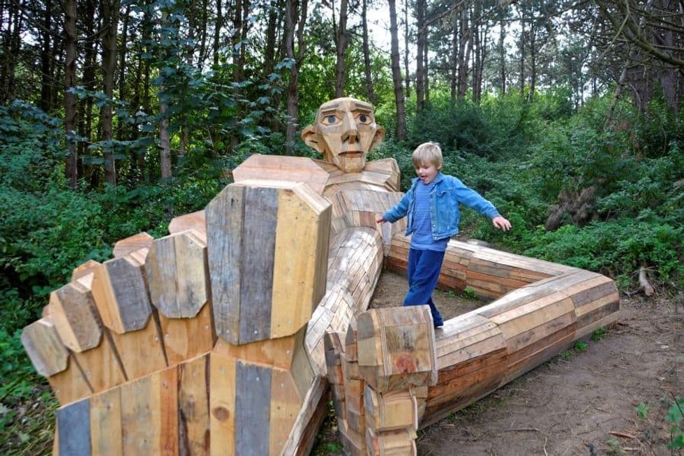 Child climbing on troll statue from Imagine Exhibitions new exhibit
