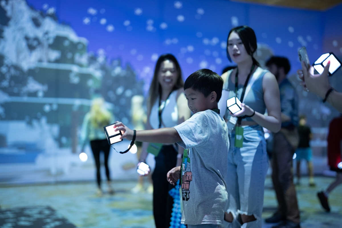 Child holding a glowing cube in an interactive exhibit with others.