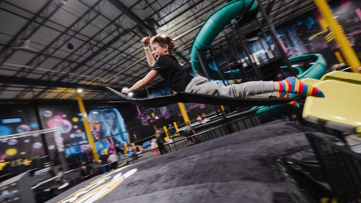 Child in colorful socks sliding at Slick City indoor playground with slides and climbing structures.