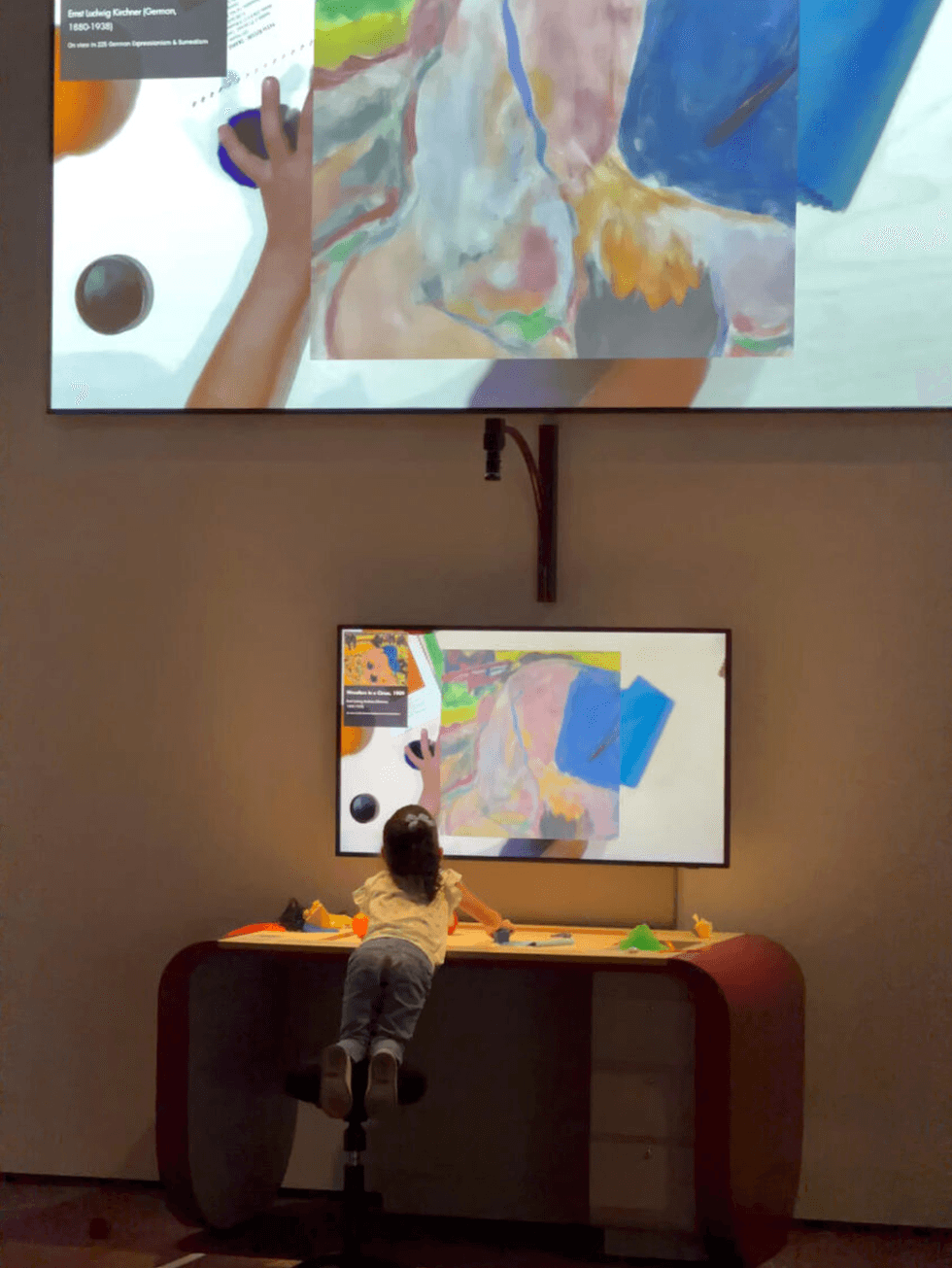 Child interacting with digital art display at a museum.