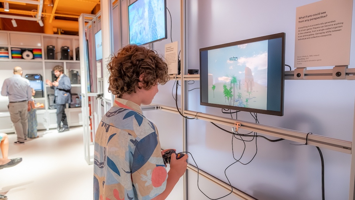 Child playing a video game on a mounted screen in a tech exhibit room.