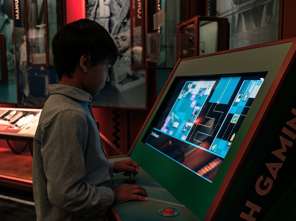 Child playing an educational game on a large interactive screen in a museum exhibit at Museum of Utah.