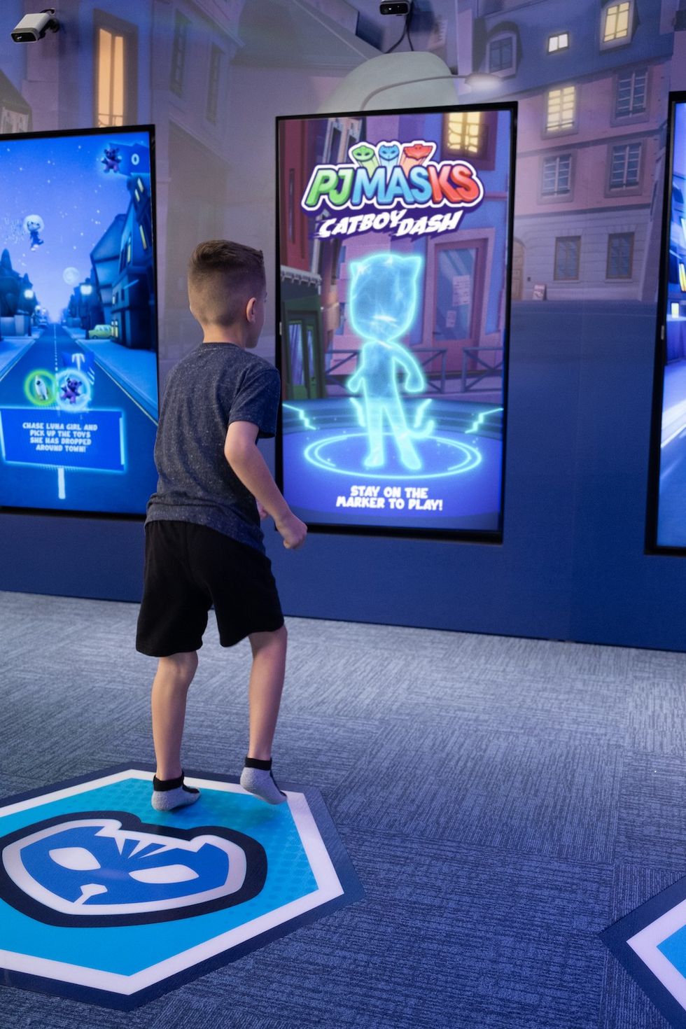 Child playing interactive "PJ Masks: Catboy Dash" game on a motion-sensor screen.