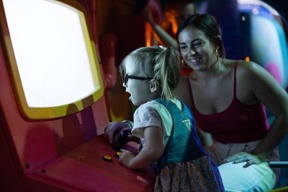 Child playing interative museum exhibit with woman smiling nearby Nauticus Aquaticus