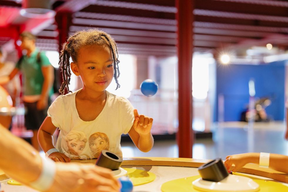 Child playing with a floating ball exhibit at a science center at the Science and Industry Museum, Manchester.