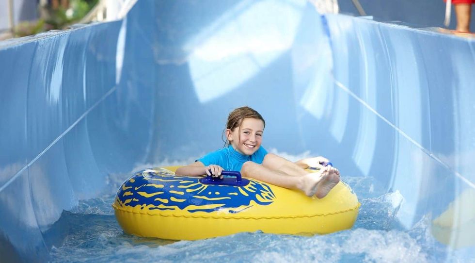 Child smiling on a yellow tube in a blue water slide at LC Swansea
