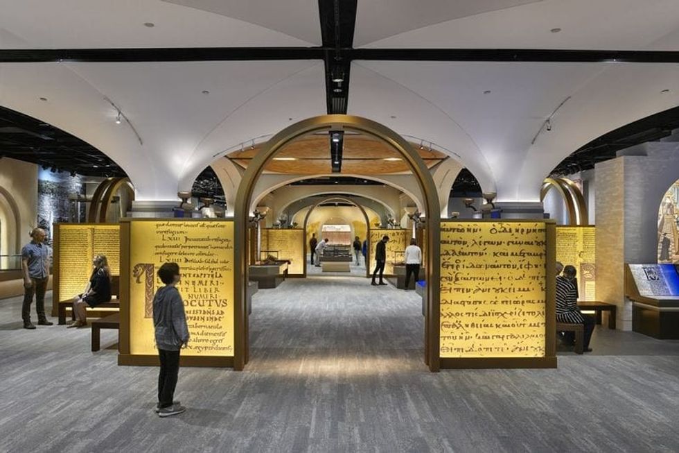 Child visitor standing in front of exhibition with Hebrew texts