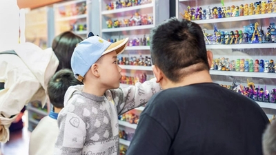 Child wearing blue cap points at toy display case in a Ninjago popup at Legoland.