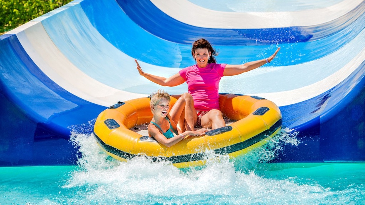 Child with mother on water slide at aquapark. Two persons on summer holiday.
