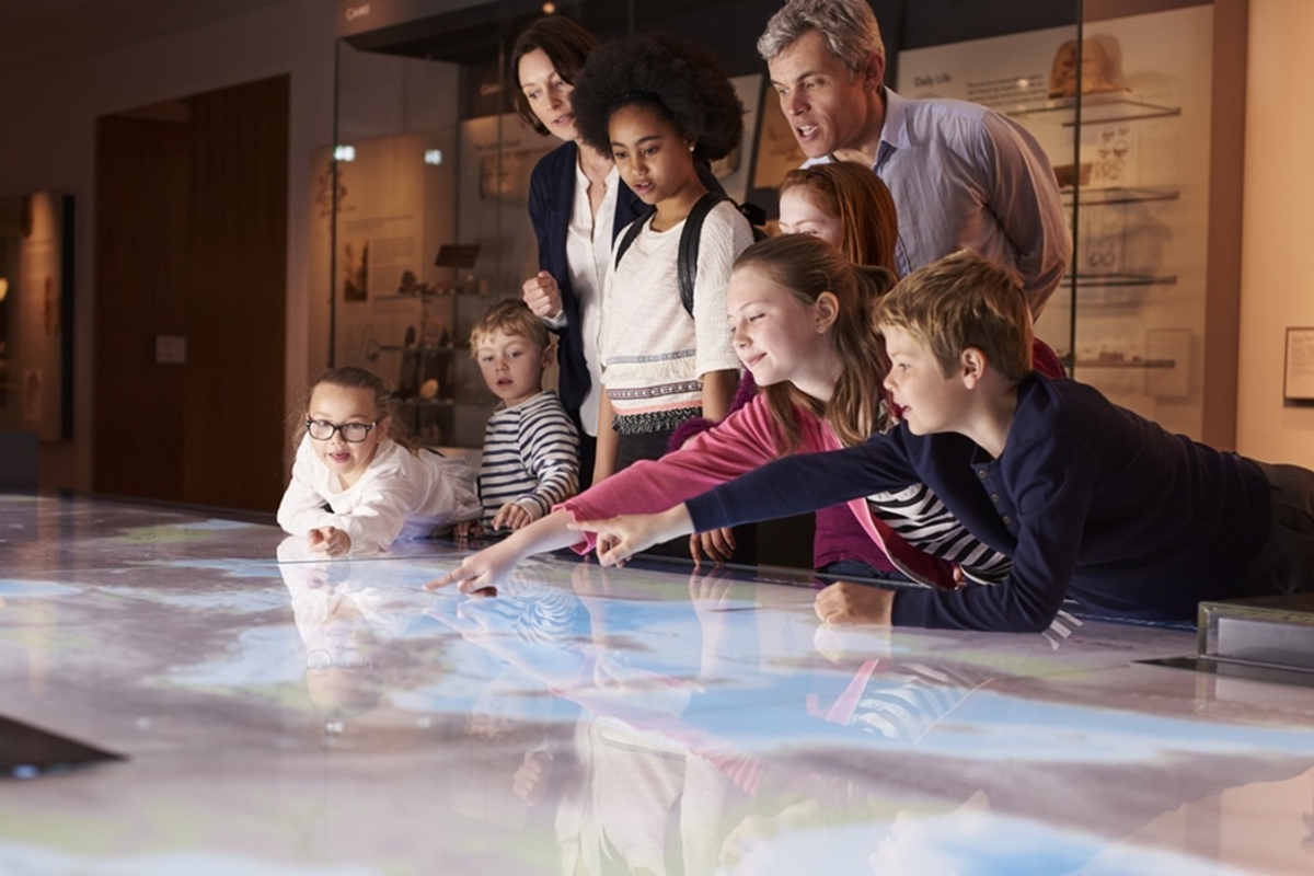 Children and adults interact with a digital map in a museum exhibit.