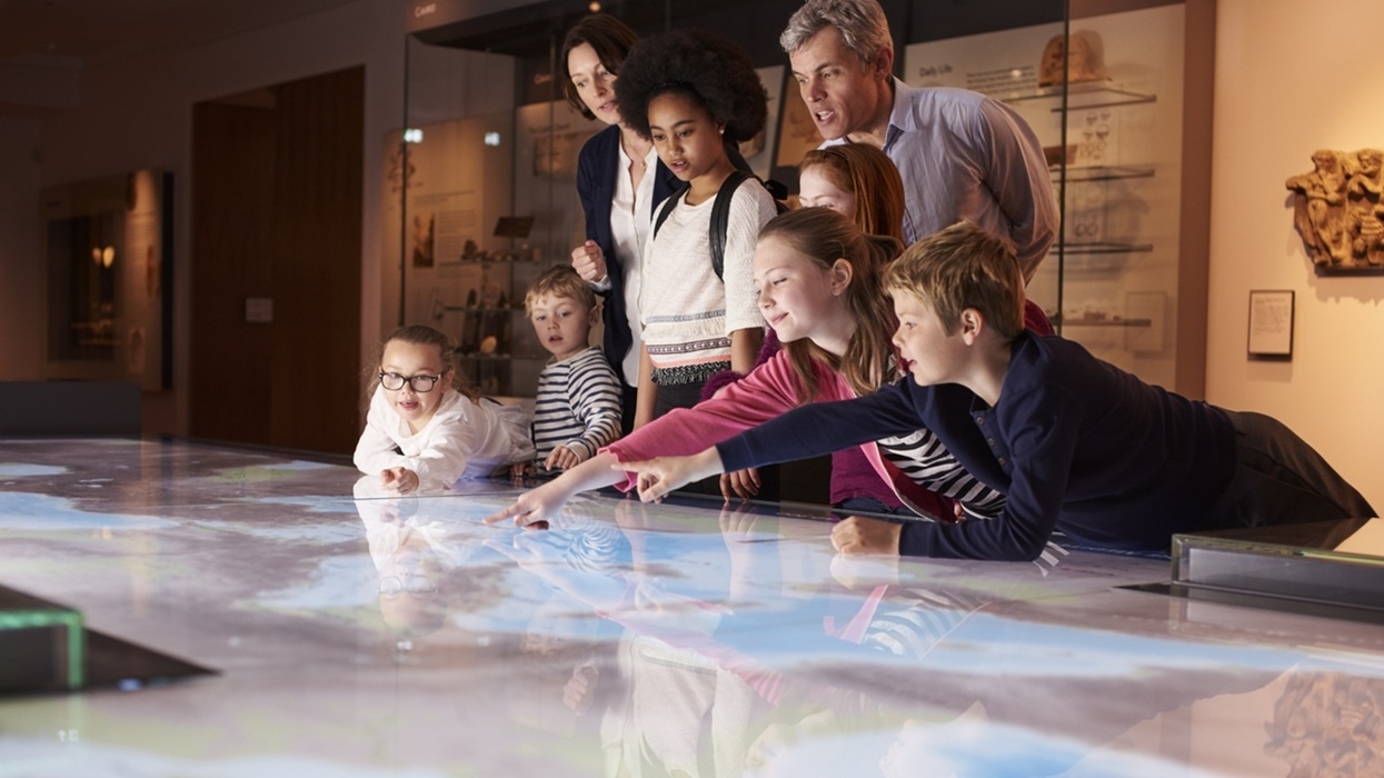Children and adults interact with a digital map in a museum exhibit.
