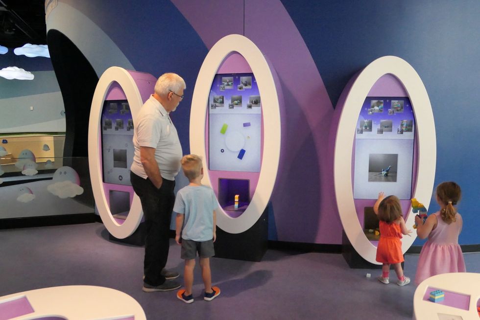 Children and an adult explore interactive displays at a museum exhibit.