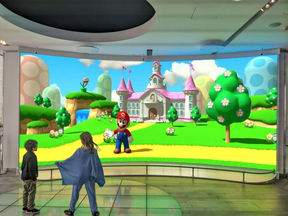 Children interact with a large Mario display at a gaming exhibit.
