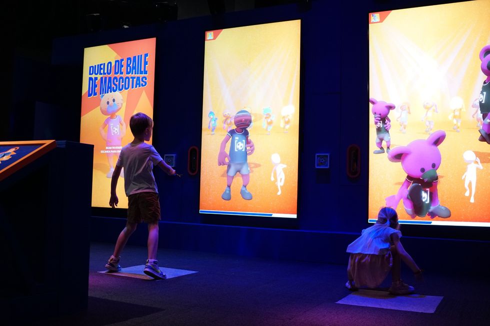 Children interact with dance game screens featuring animated mascots.
