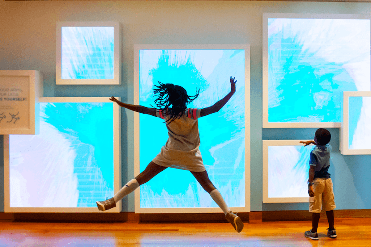 Children interact with dynamic blue screens in a gallery exhibit at High Museums