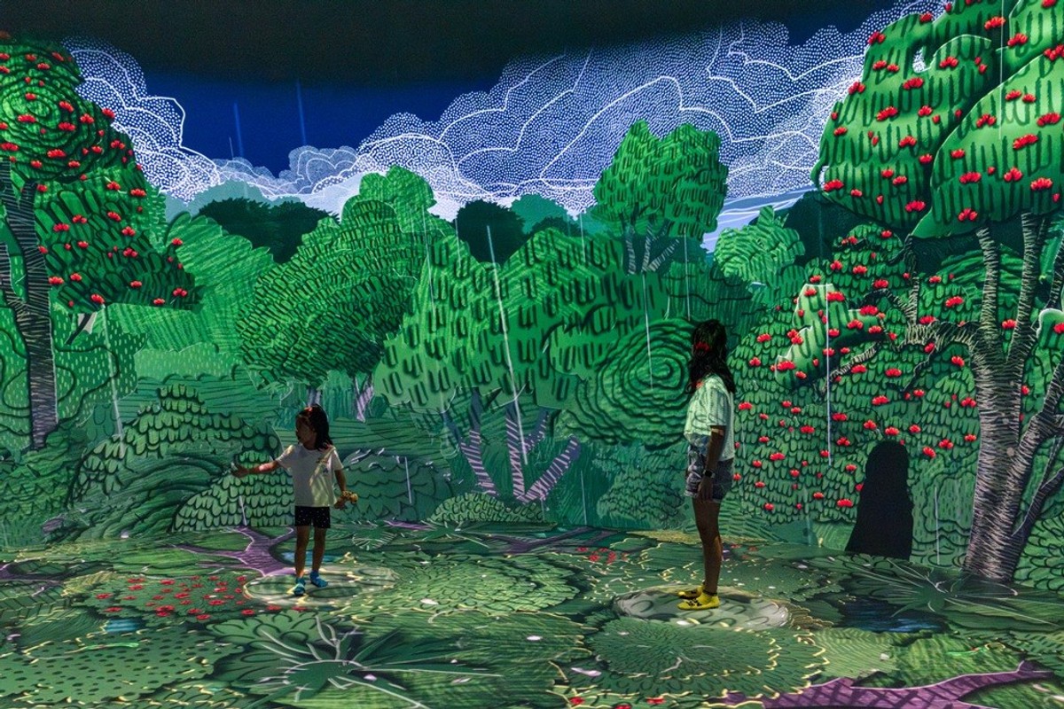Children interacting with a colorful, immersive digital forest art installation.