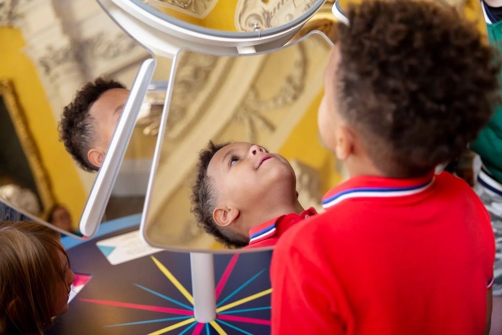 Children look at ceiling through mirror at Sudbury Hall