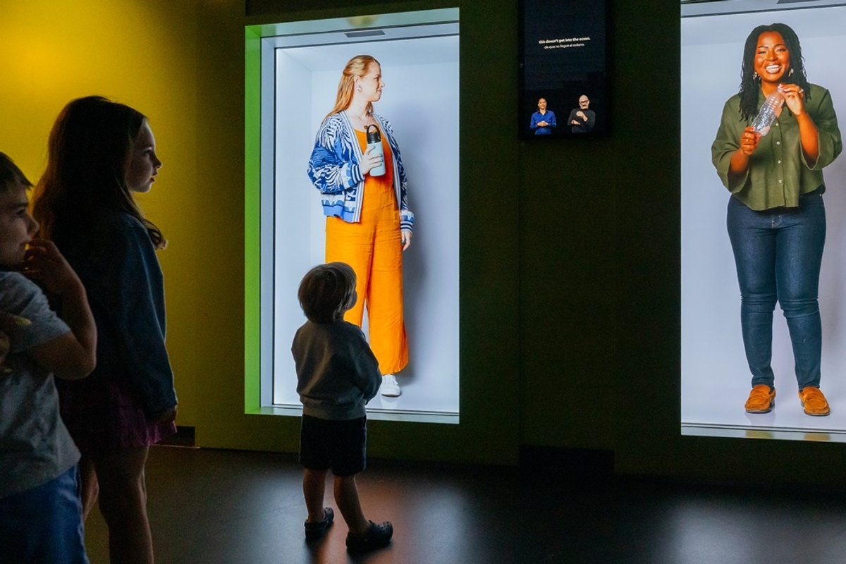 Children observing two illuminated exhibits with people in colourful outfits at the National Geographic Museum of Exploration