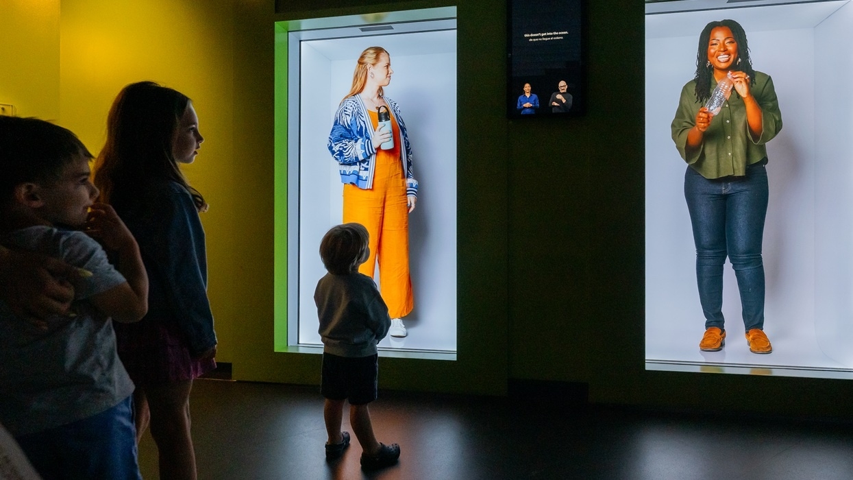 Children observing two illuminated exhibits with people in colourful outfits at the National Geographic Museum of Exploration