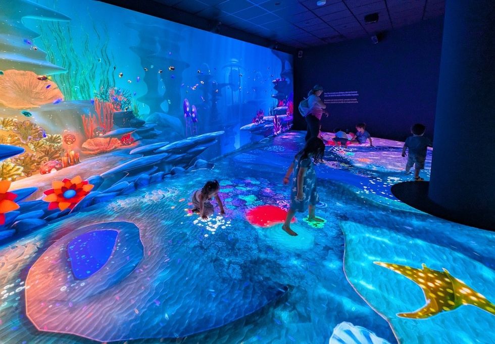 Children play in an interactive, underwater-themed digital exhibit with vivid ocean projections.
