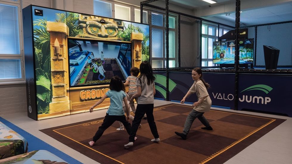 Children playing an interactive game named Groundfall on a large screen at an indoor activity center.