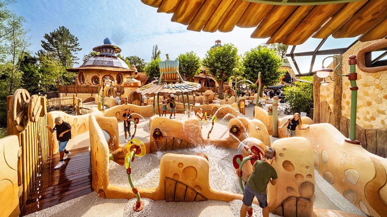 Children playing in a whimsical, nature-themed water park with sprayers and playful structures.