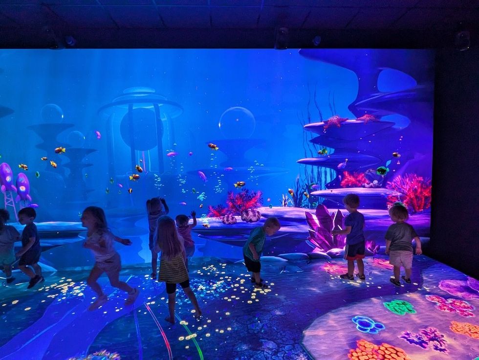 Children playing in an interactive, colorful underwater-themed room.