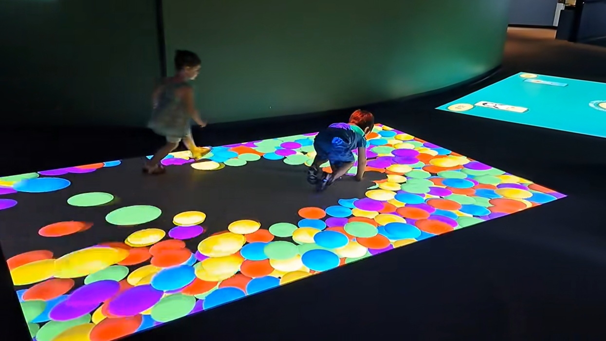 Children playing on a colourful interactive floor display from Breeze Creative
