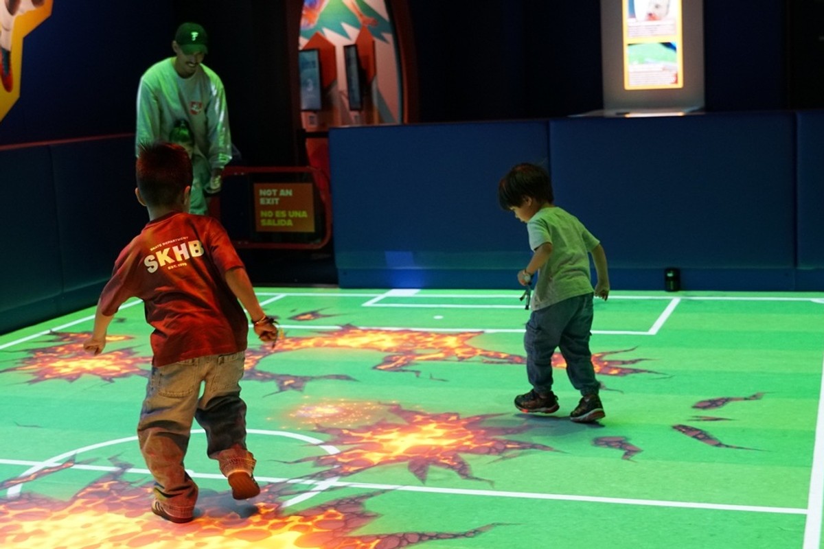 Children playing on an interactive, projected floor game with animated graphics.