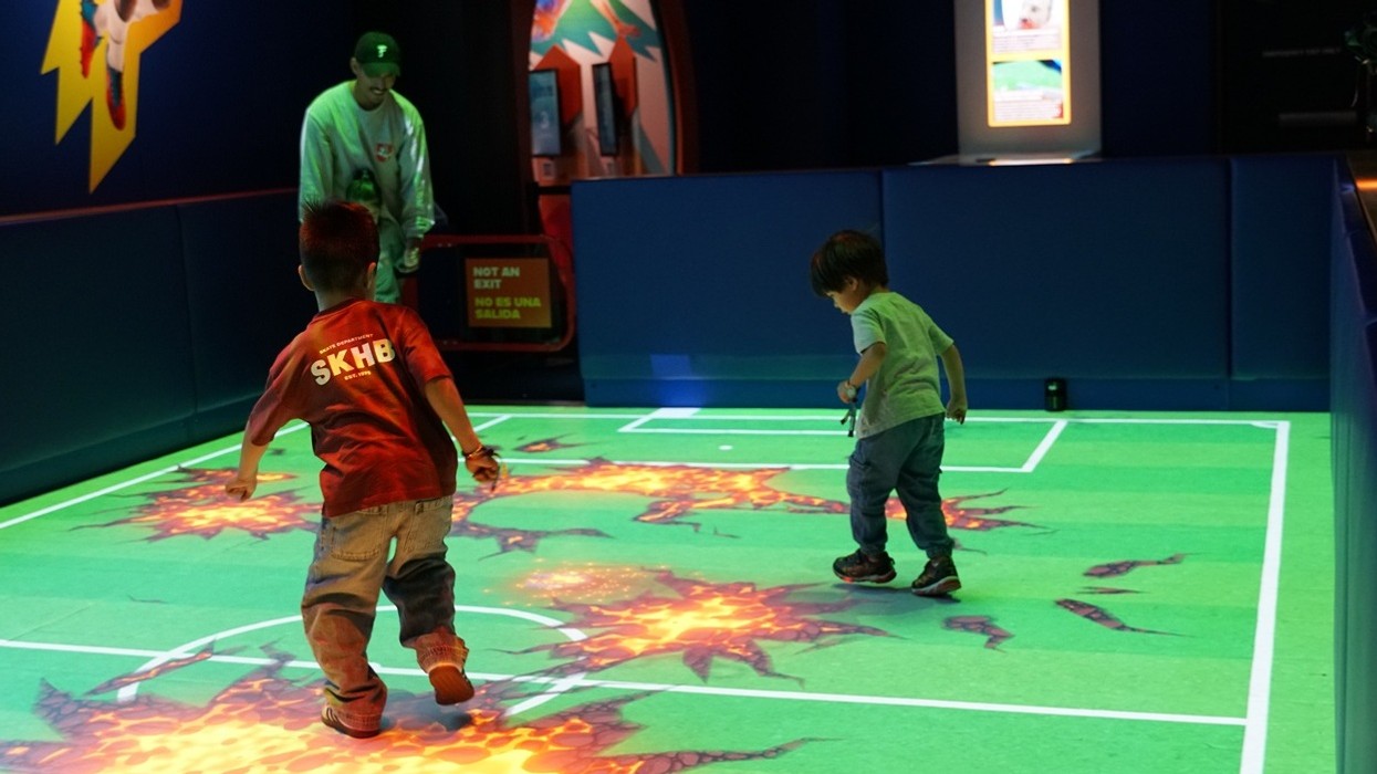 Children playing on an interactive, projected floor game with animated graphics.
