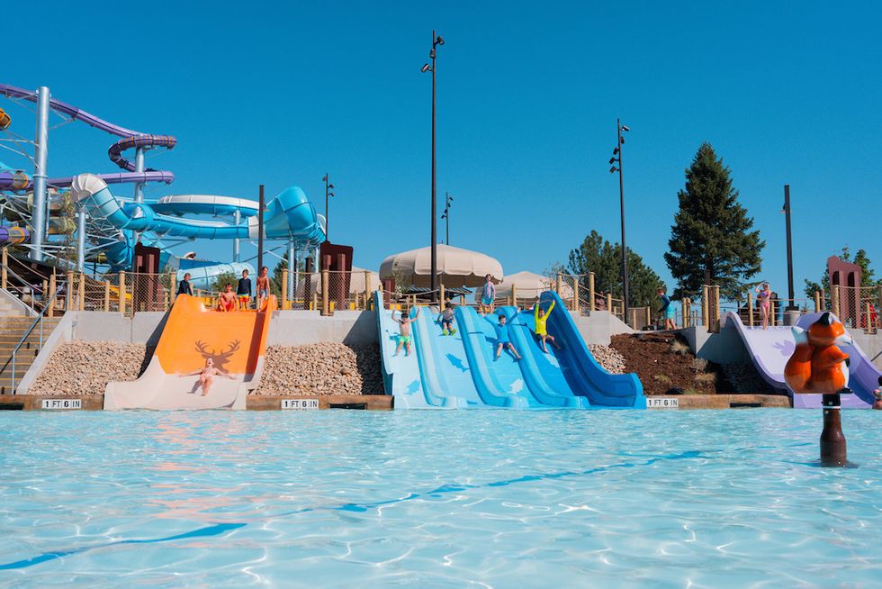 Children playing on colorful water slides under a clear blue sky.
