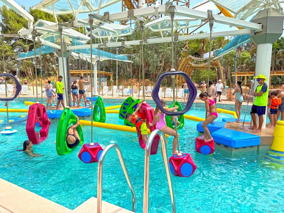 Children playing on colourful floating obstacles in a busy outdoor pool at PortAventura World's Caribe Aquatic Park