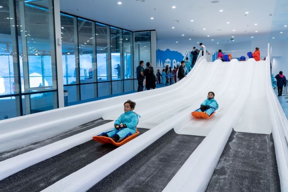 children playing on ice slides at Frostland ICE NOW