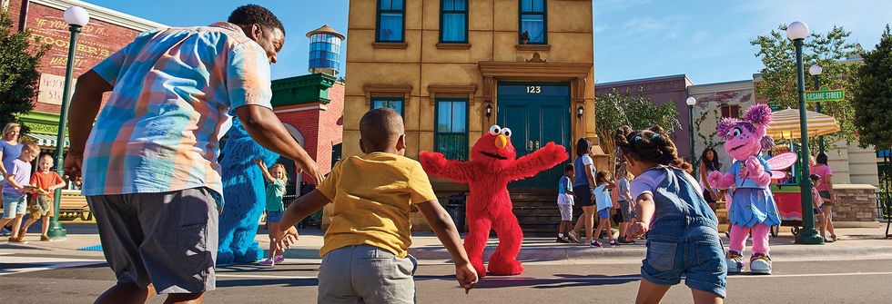 Children playing with Elmo and characters on a sunny street.
